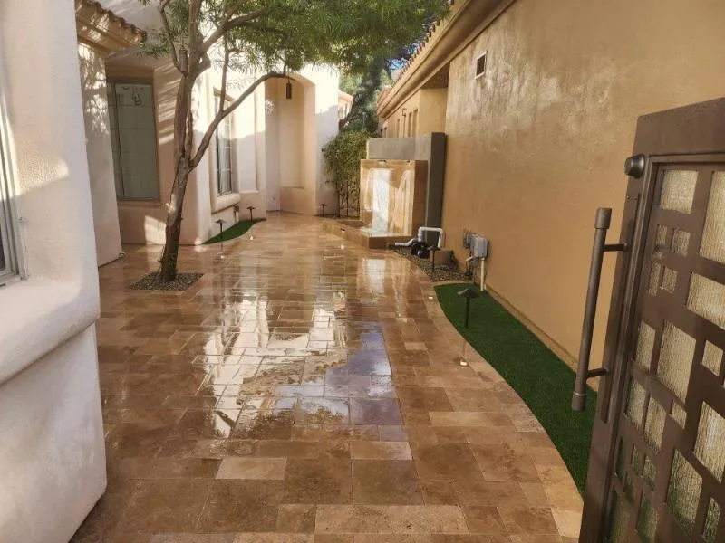 Travertine paver courtyard with mixed-format stone, mature tree, and synthetic turf borders