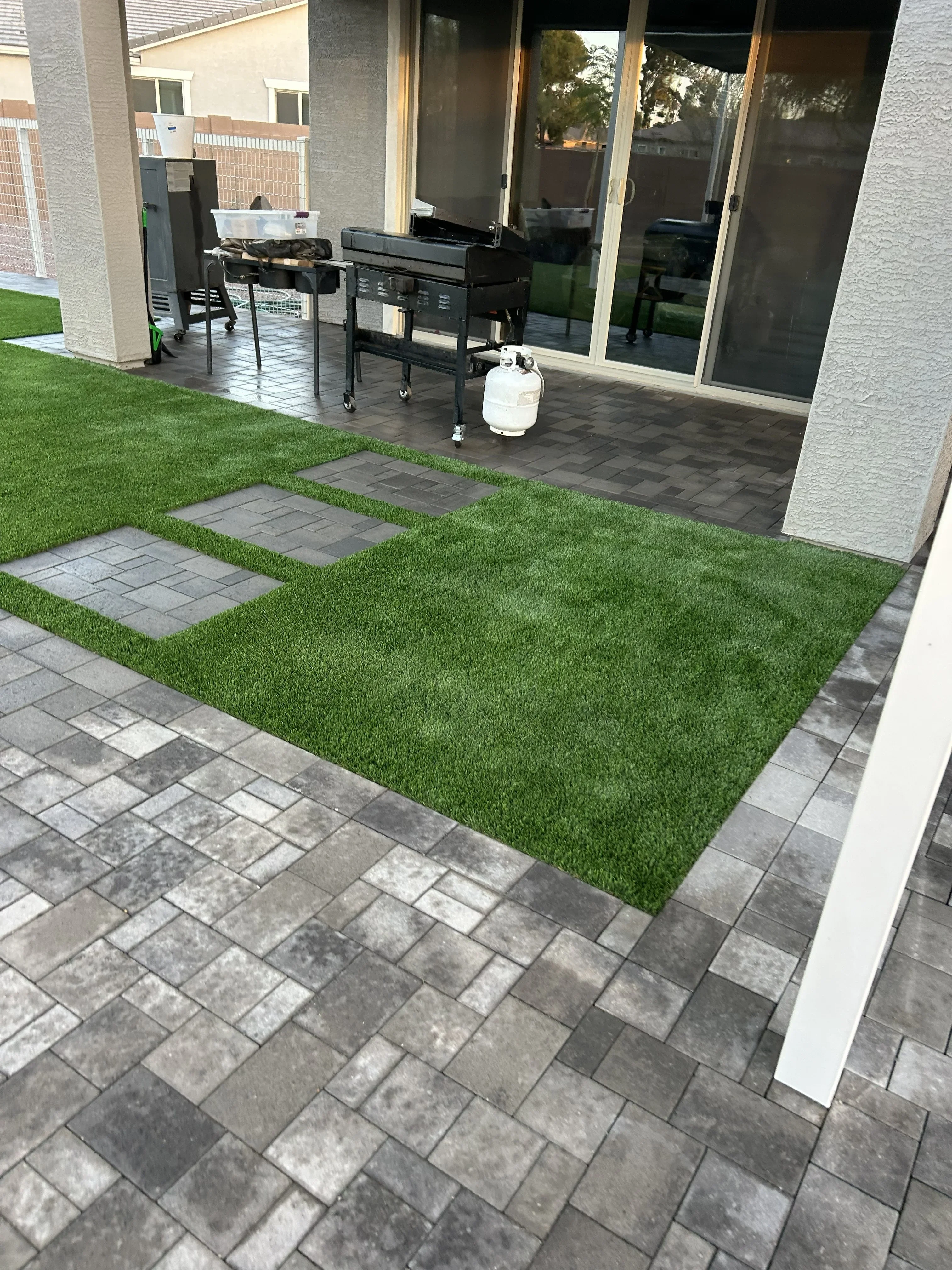 Synthetic turf lawn with concrete paver patio and stepping stone pathway